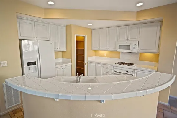 a kitchen with stainless steel appliances granite countertop a sink a refrigerator and white cabinets