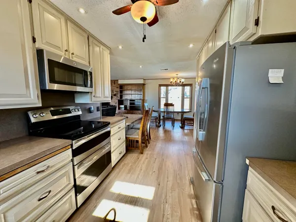a kitchen with stainless steel appliances granite countertop a stove top oven a sink dishwasher a dining table and chairs with wooden floor