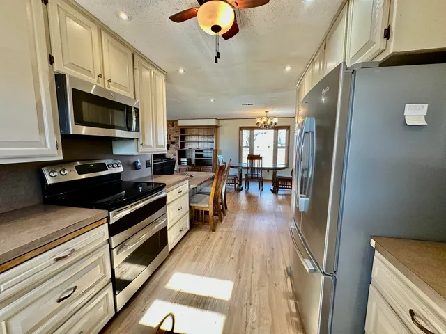 a kitchen with stainless steel appliances granite countertop a stove top oven a sink dishwasher a dining table and chairs with wooden floor