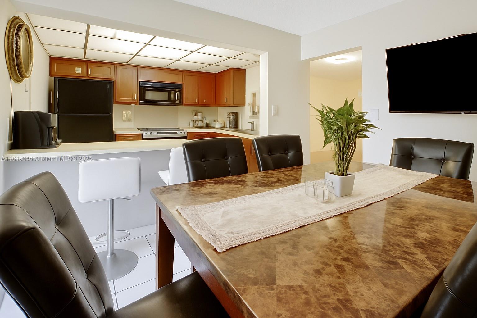 13731 Southwest 84th Street, Unit B Miami, FL 33143 - Photo 6 of 13 a kitchen with a table chairs refrigerator and microwave
