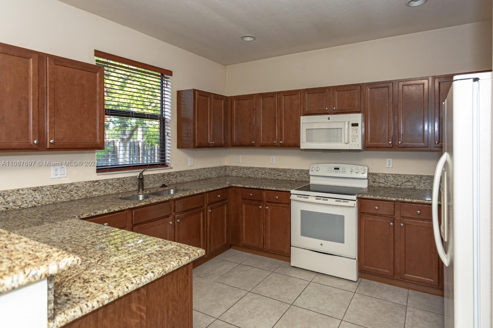 9019 Southwest 227th Terrace Cutler Bay, FL 33190 - Photo 6 of 9 a kitchen with stainless steel appliances granite countertop wooden cabinets a sink and a stove