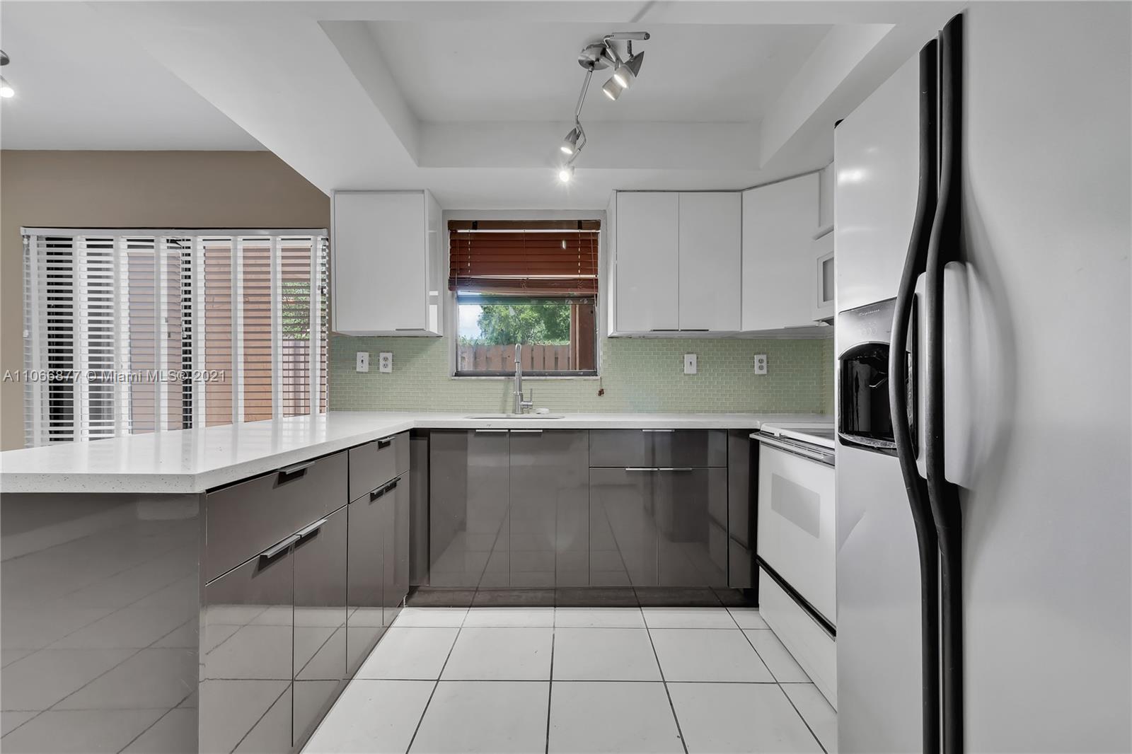 11820 Southwest 80th Street, Unit 312 Miami, FL 33183 - Photo 14 of 43 a kitchen with a sink a refrigerator and cabinets