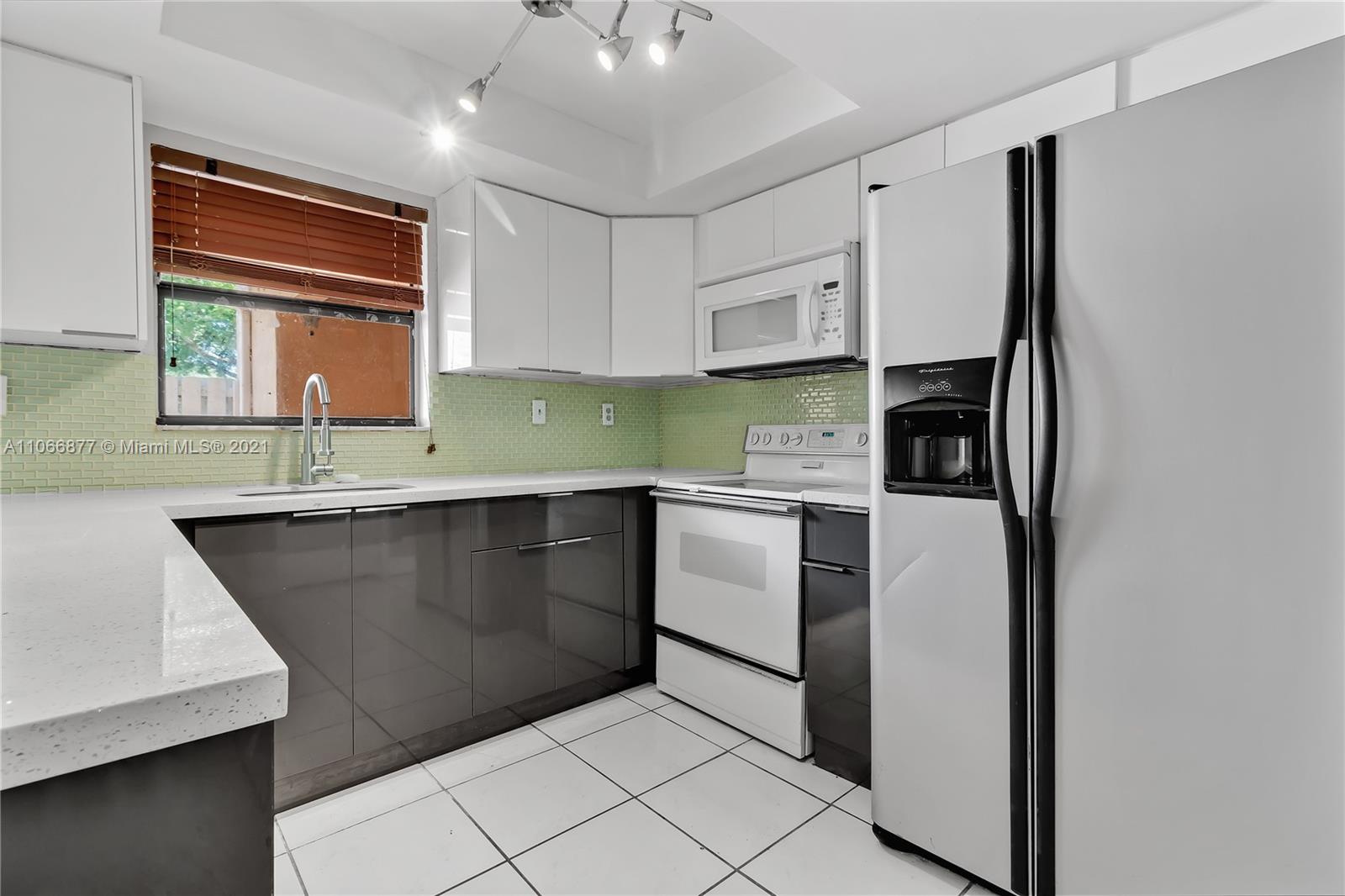 11820 Southwest 80th Street, Unit 312 Miami, FL 33183 - Photo 15 of 43 a kitchen with a sink refrigerator and cabinets