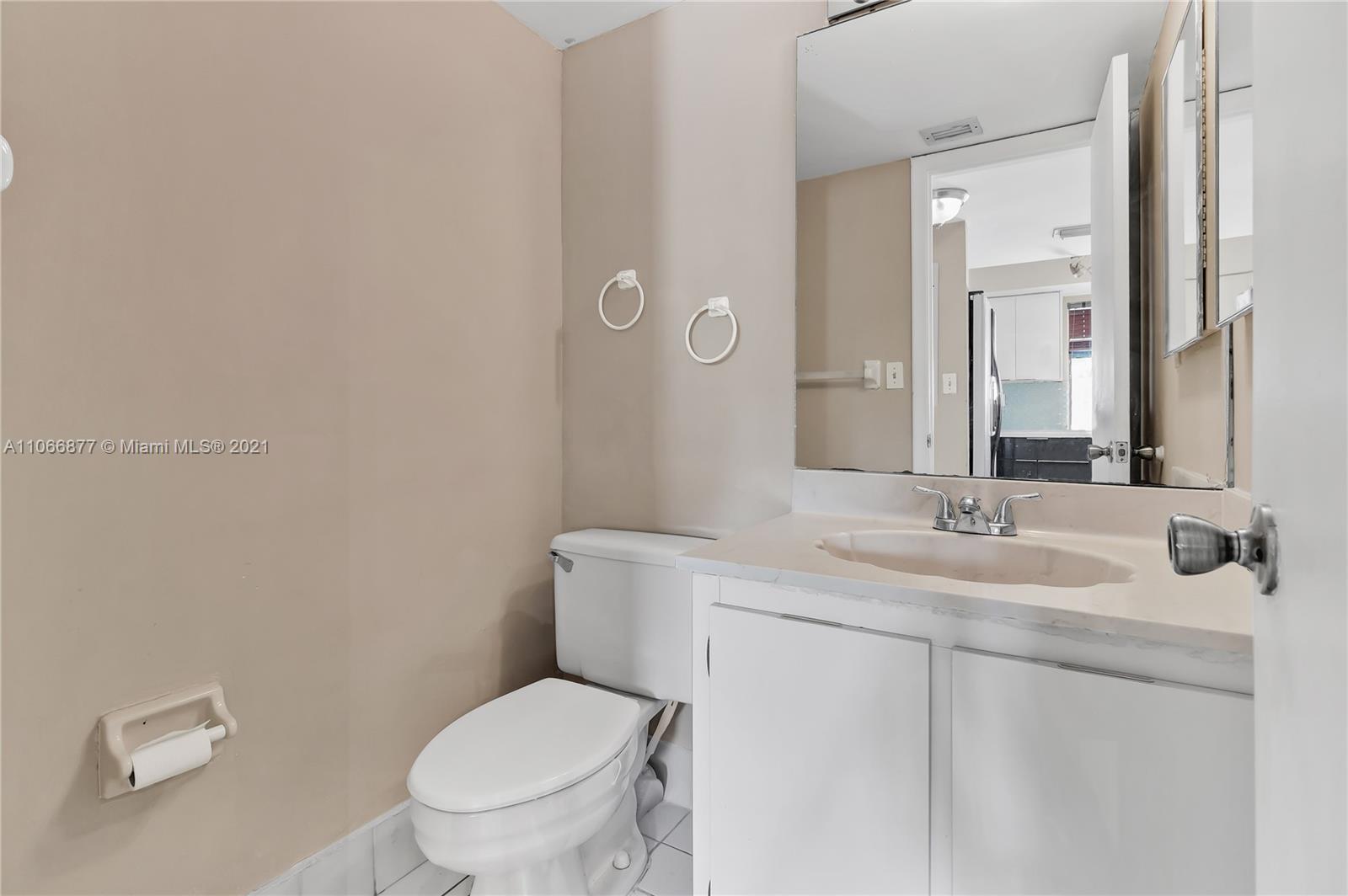 11820 Southwest 80th Street, Unit 312 Miami, FL 33183 - Photo 18 of 43 a bathroom with a toilet a sink and mirror