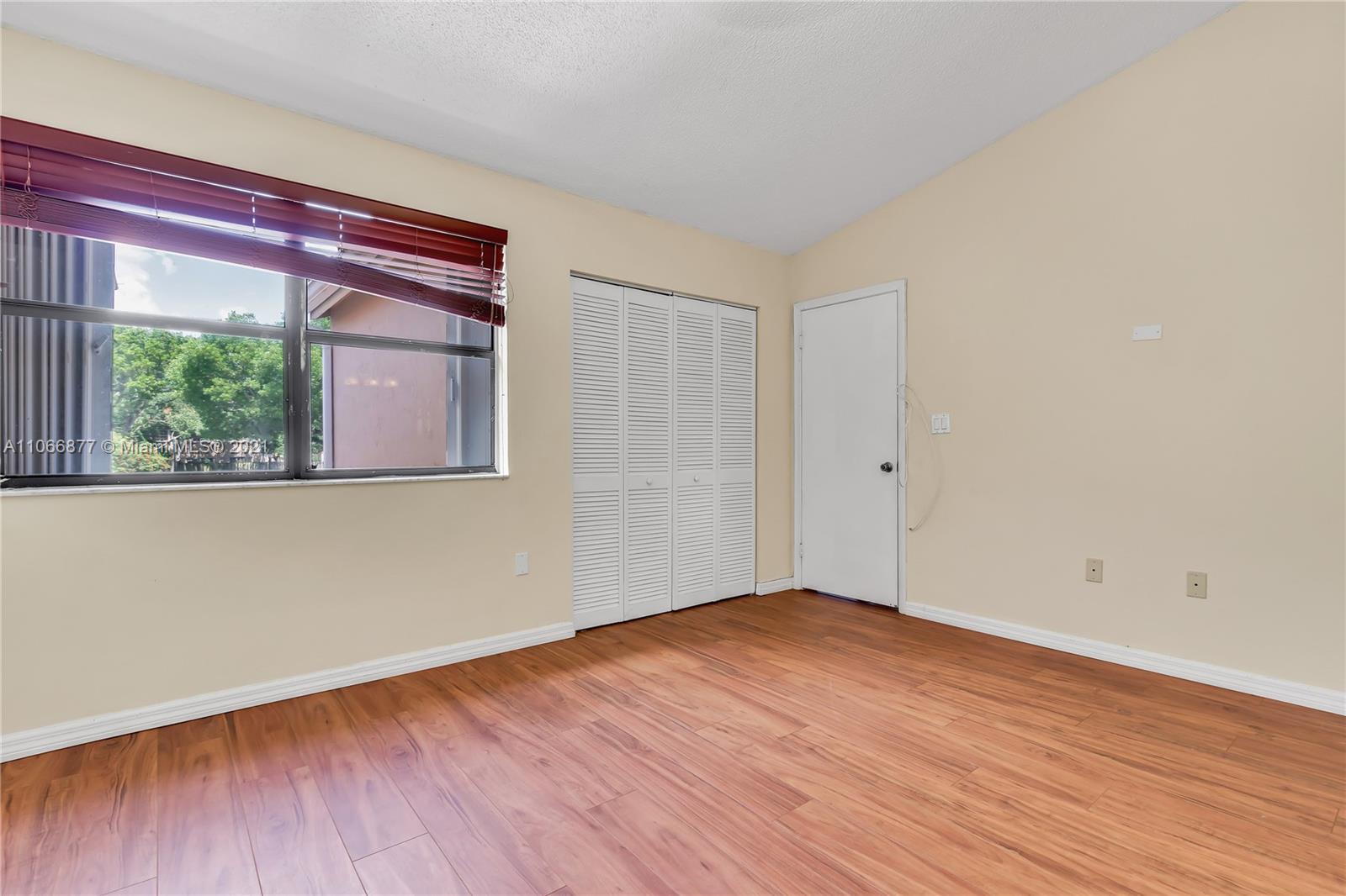 11820 Southwest 80th Street, Unit 312 Miami, FL 33183 - Photo 28 of 43 a view of an empty room with wooden floor and a window