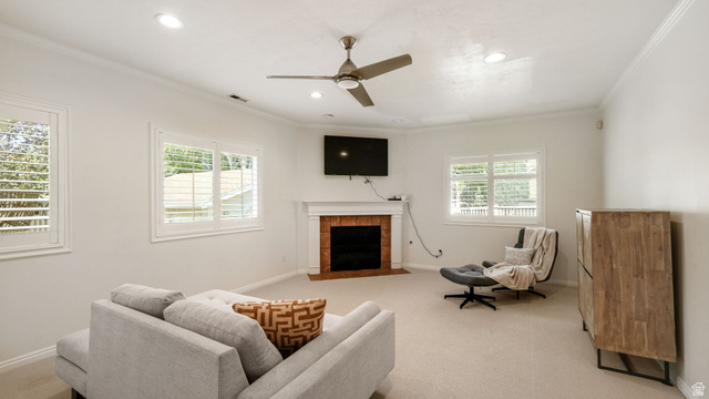 11128 South Barrett Pk Circle Sandy, UT 84092 - Photo 12 of 36 Spacious living area featuring a central fireplace with a brick surround and white mantel, plantation shutters on multiple windows, recessed lighting, and a ceiling fan