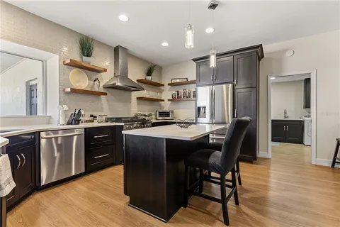 a kitchen with stainless steel appliances granite countertop a table chairs refrigerator and microwave