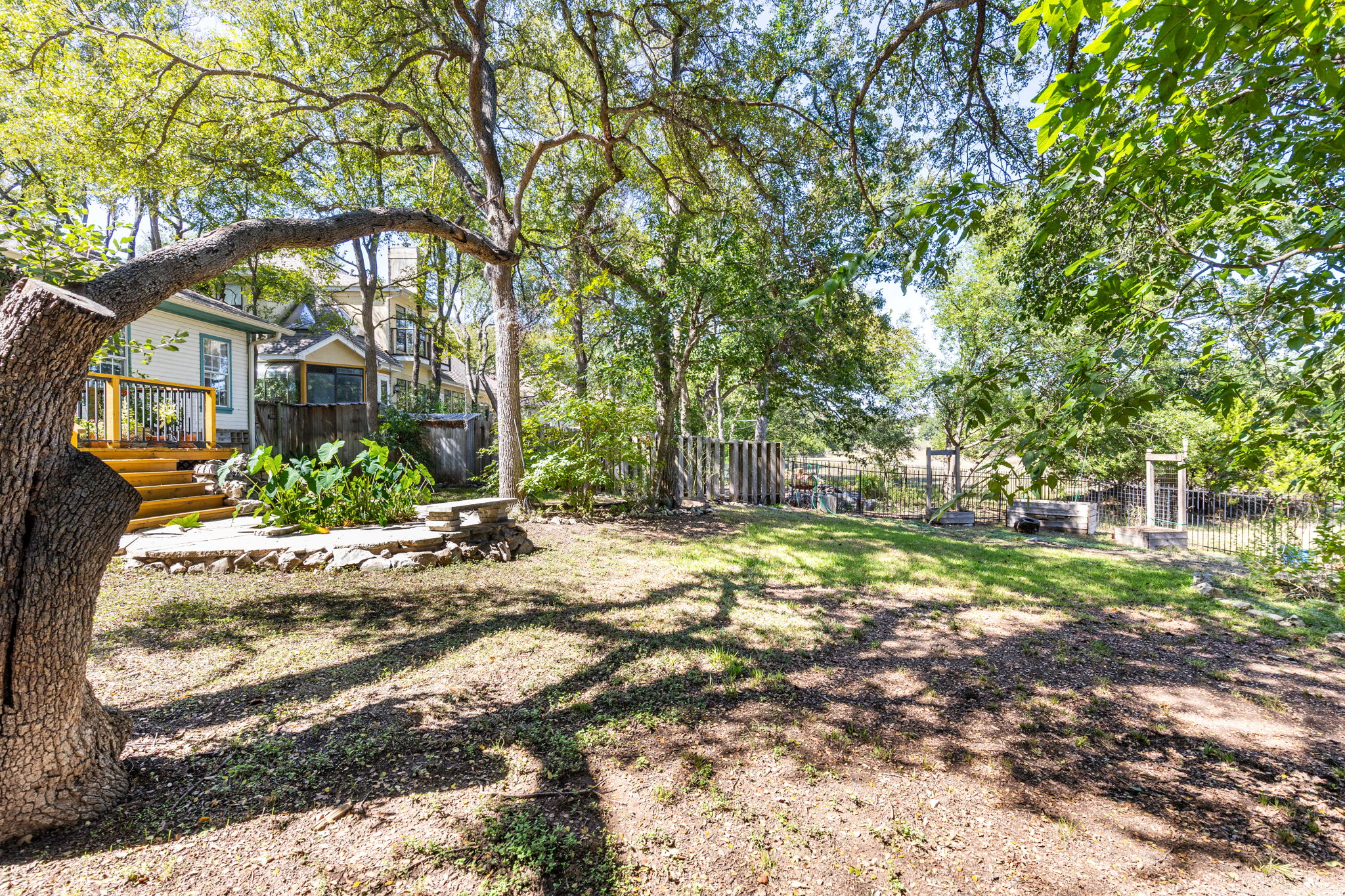 134 Canyon Road Georgetown, TX 78628 - Photo 33 of 40 Mature trees shade a spacious lawn featuring a stone patio and wooden deck.