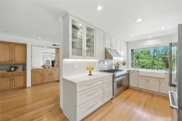 a kitchen with a stove a sink and white cabinets with wooden floor
