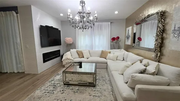 a living room with furniture a flat screen tv and a chandelier