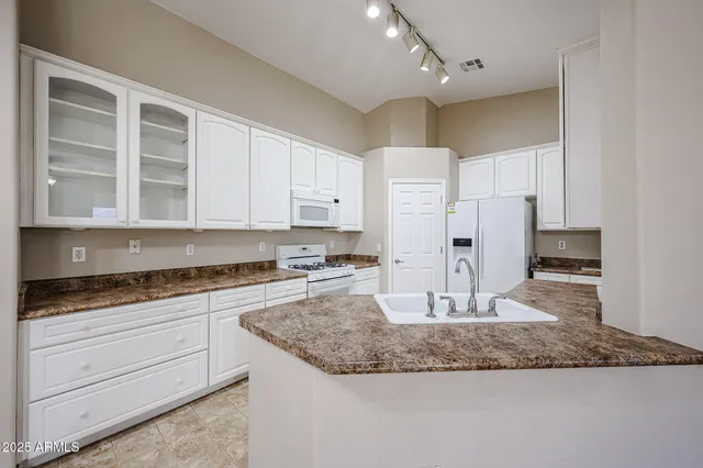 a kitchen with white cabinets and sink