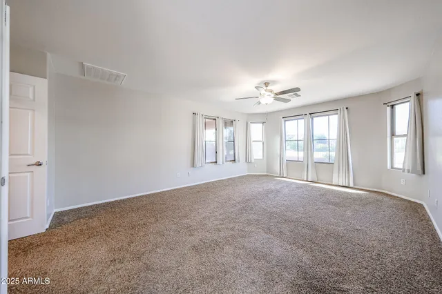 an empty room with windows and chandelier fan