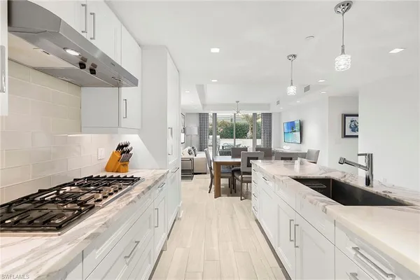 a kitchen with counter top space a sink a stove and wooden floor