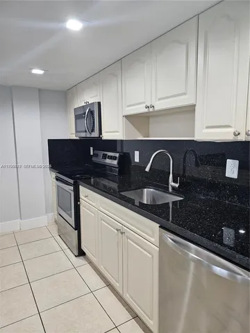 a kitchen with white cabinets a sink and white appliances