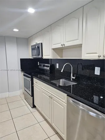a kitchen with white cabinets a sink and white appliances