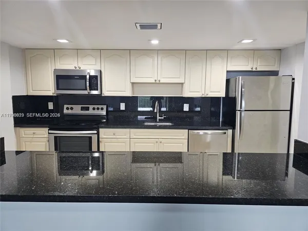 a kitchen with kitchen island granite countertop a refrigerator a stove and a sink