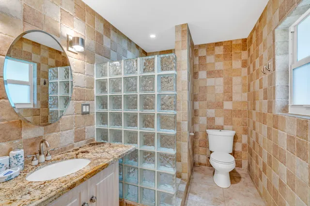 a bathroom with a granite countertop sink a toilet and a mirror