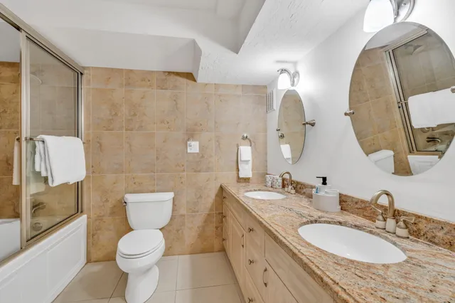 a bathroom with a granite countertop toilet sink and mirror