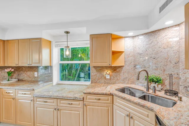a kitchen with granite countertop a sink a counter top space cabinets and stainless steel appliances