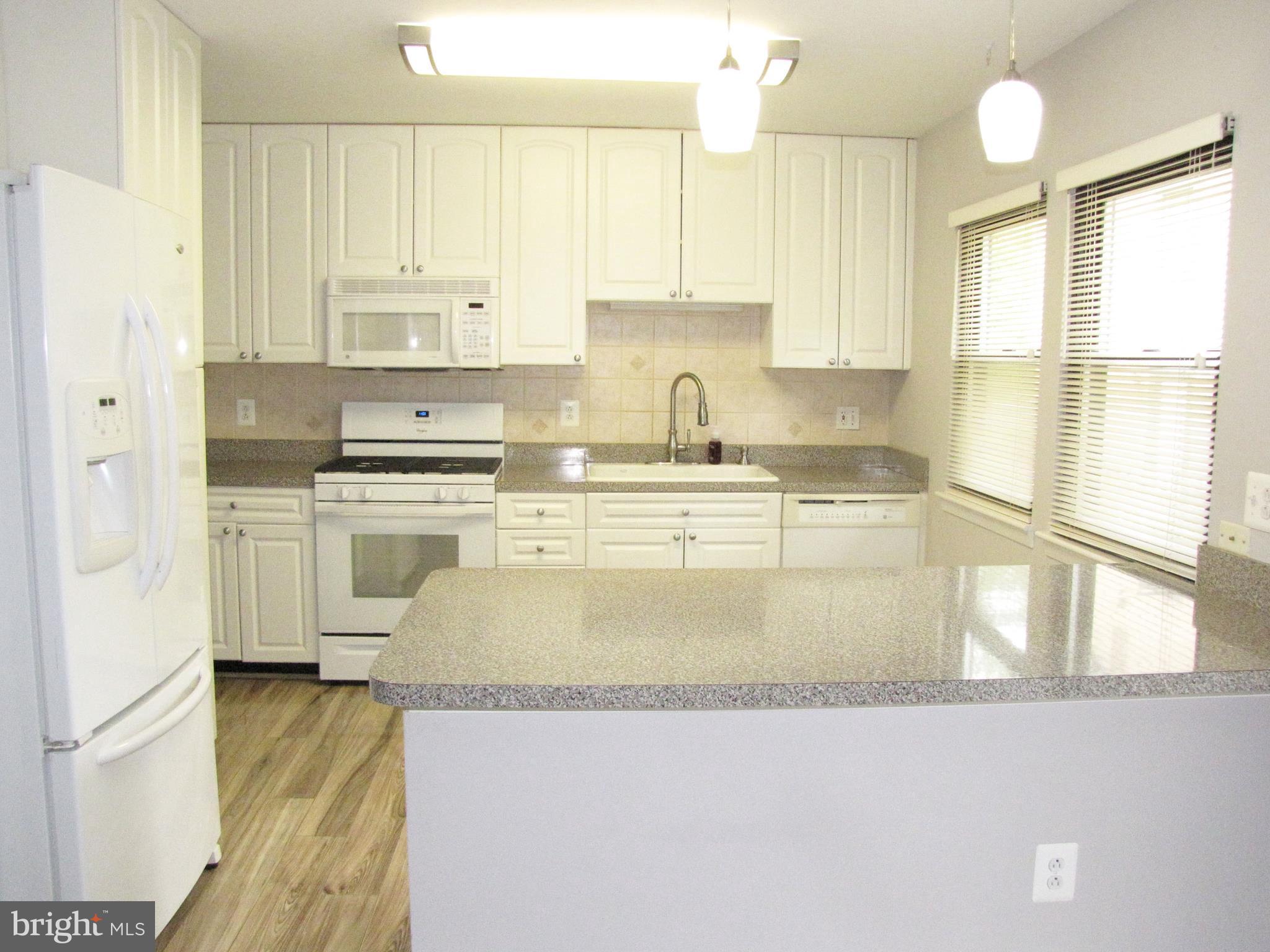 9600 Farewell Road Columbia, MD 21045 - Photo 6 of 18 a large kitchen with stainless steel appliances granite countertop a stove a sink dishwasher and white cabinets with wooden floor