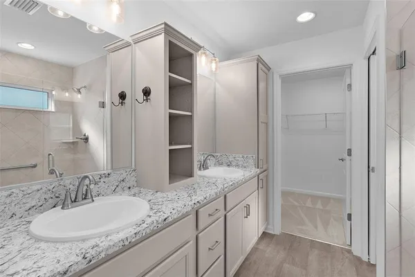 a bathroom with a granite countertop double vanity sink and mirror