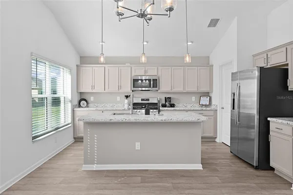 a kitchen with stainless steel appliances granite countertop a sink a stove a refrigerator cabinets and a window