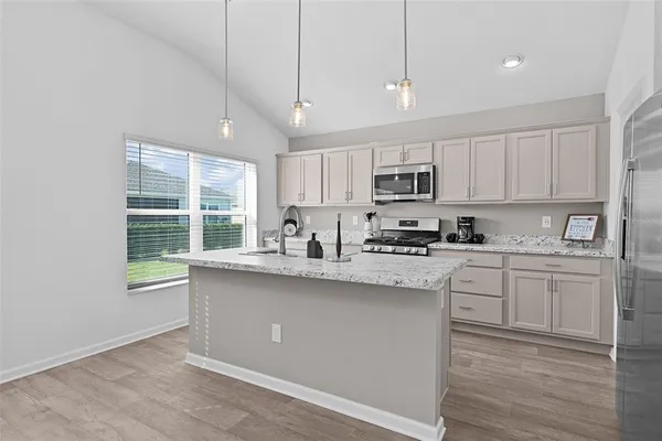 a kitchen with stainless steel appliances granite countertop a stove a sink dishwasher a refrigerator and a microwave oven with wooden floor