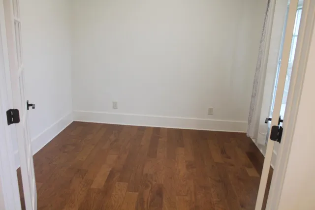 an empty room with wooden floor and window