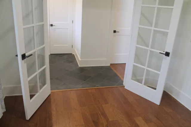 a view of an empty room with wooden floor and a hallway