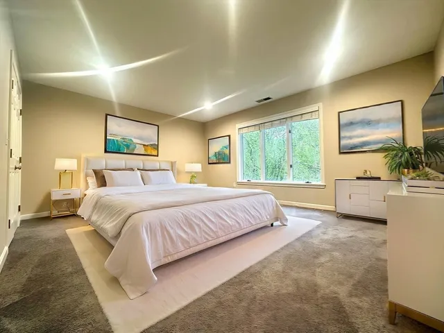 a bedroom with a large bed and a flat tv screen on dresser
