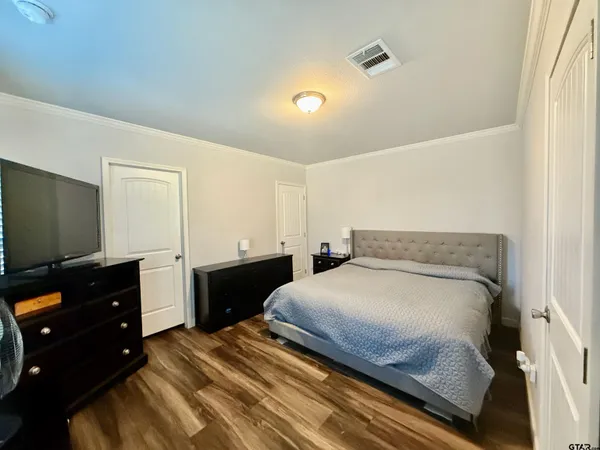 a bedroom with a bed and a flat tv screen on dresser