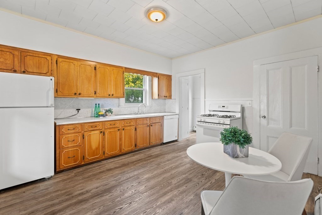 21 Boardman Street, Unit 1 Salem, MA 01970 - Photo 8 of 19 a kitchen with stainless steel appliances granite countertop a sink a stove a refrigerator with a dining table and chairs