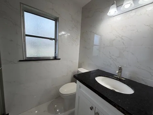 a bathroom with a granite countertop sink and a toilet