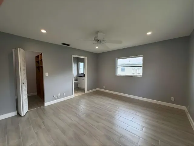 an empty room with wooden floor and windows