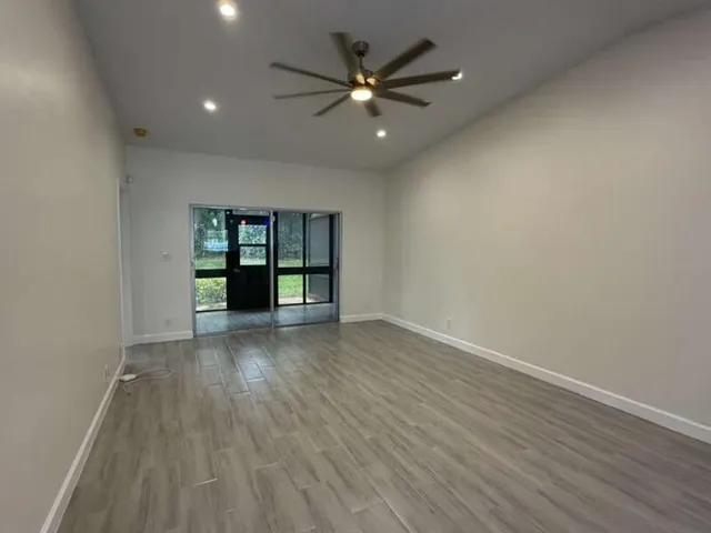 a view of an empty room with a window and wooden floor