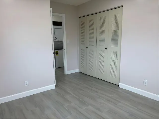 a view of an empty room with wooden floor and closet