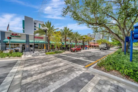 a view of road with card parked on side and retail shops