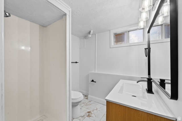 2267 West 4350th Street South Roy, UT 84067 - Photo 27 of 32 Bathroom with vanity, a textured ceiling, a stall shower, and light marble finish floors