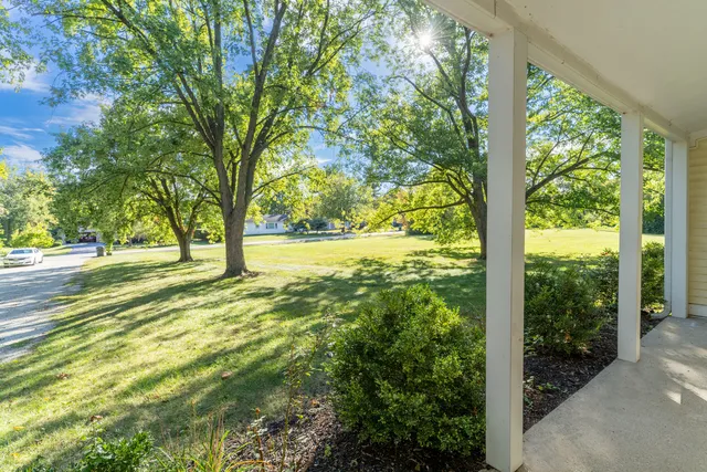a view of a house with a big yard and large trees