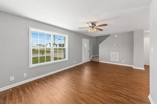 a view of an empty room with a window and wooden floor