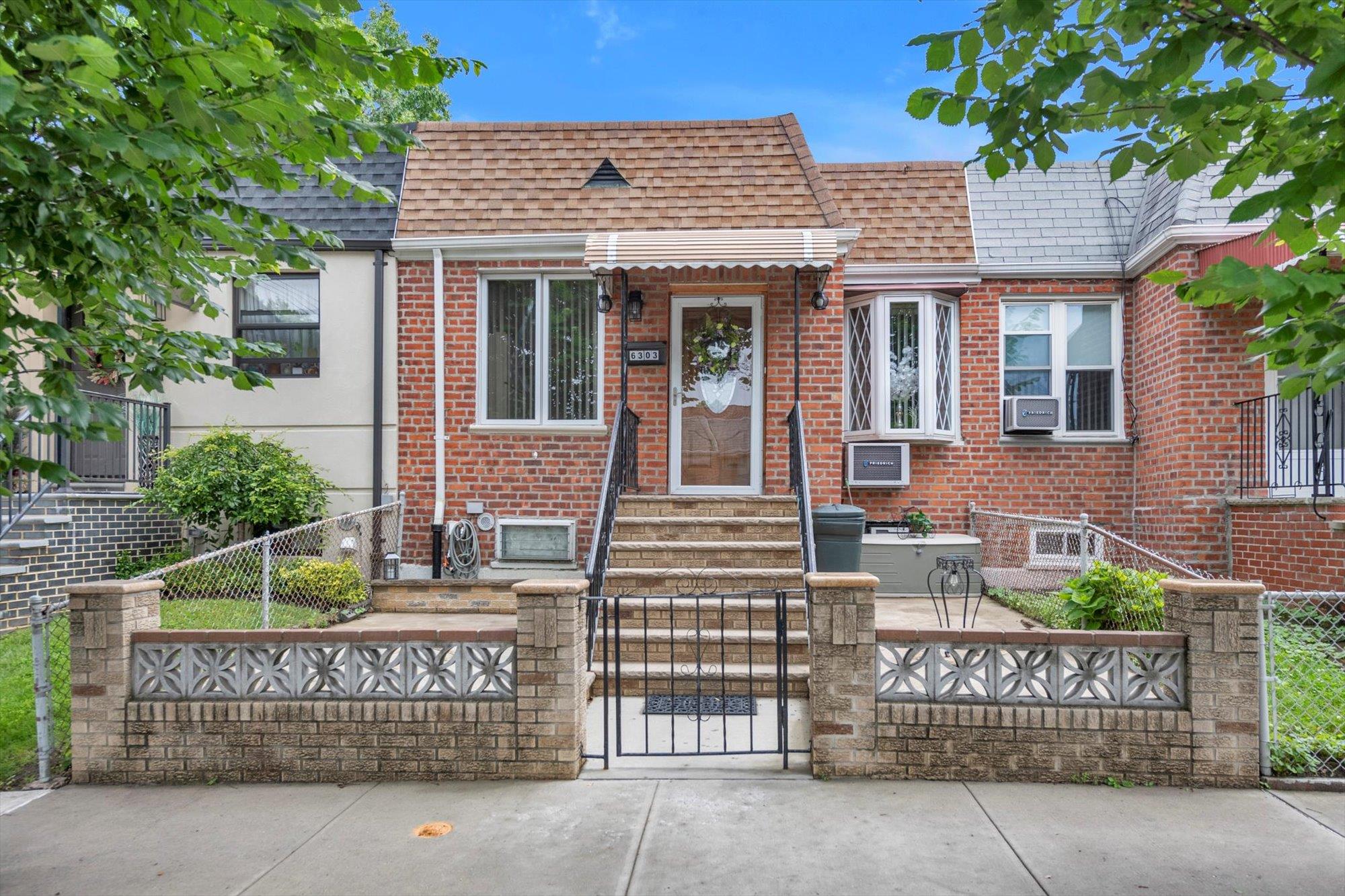 63-03 74th Street Queens, NY 11379 - Photo 1 of 15 View of front facade featuring a fenced front yard, a shingled roof, and brick siding