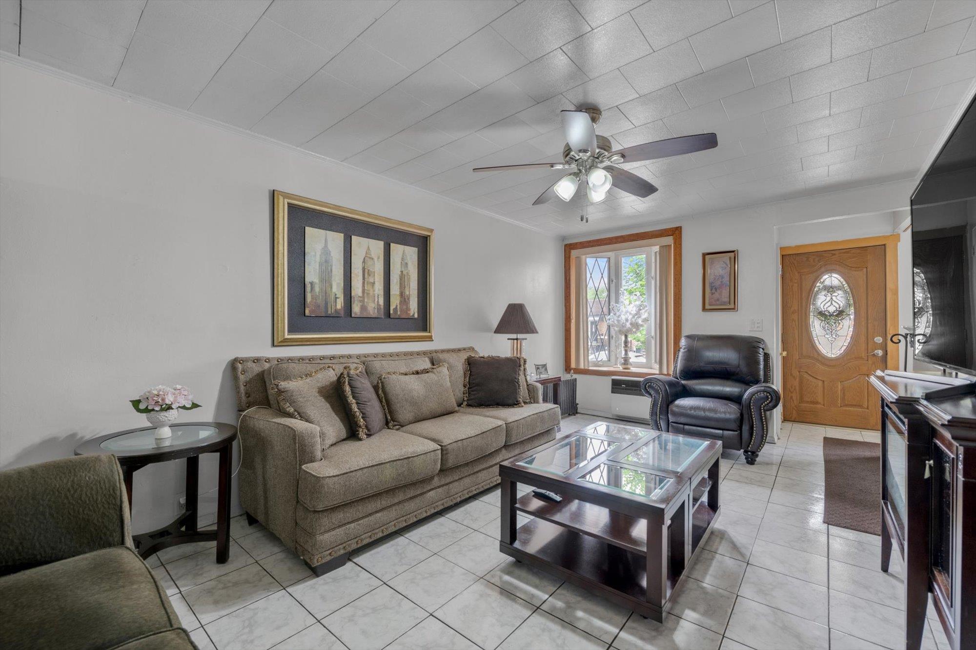 63-03 74th Street Queens, NY 11379 - Photo 4 of 15 Living area featuring a ceiling fan, light tile patterned floors, and ornamental molding