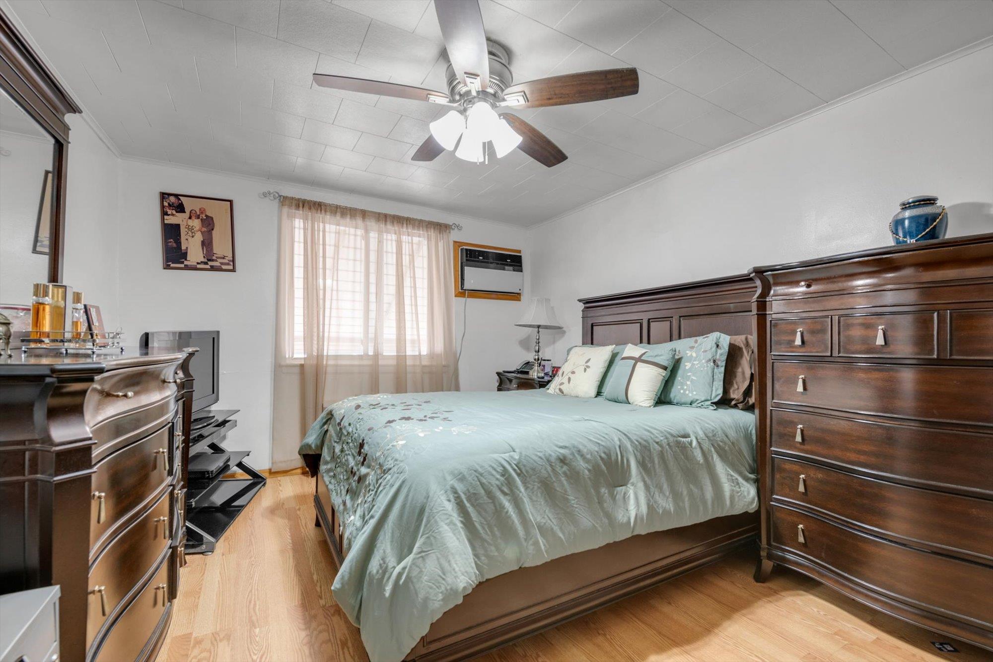 63-03 74th Street Queens, NY 11379 - Photo 9 of 15 Bedroom featuring a wall unit AC, light wood-style floors, crown molding, and ceiling fan