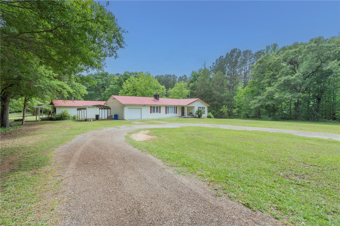 This ranch-style home features a vibrant red roof, nestled amidst lush greenery and a spacious yard.