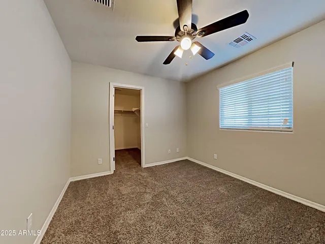 a view of an empty room with a chandelier fan