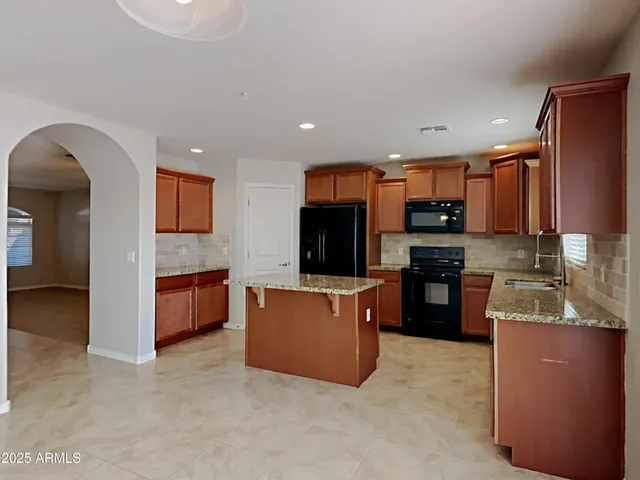 a kitchen with stainless steel appliances kitchen island granite countertop a refrigerator and a stove top oven
