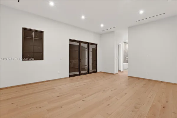 a view of an empty room with wooden floor and windows