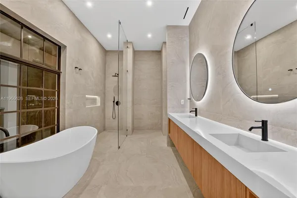 a en suite bathroom with a double vanity sink a large mirror and a bathtub