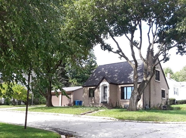 a front view of a house with a garden and tree