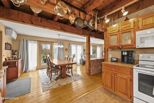 a dining hall with stainless steel appliances granite countertop a stove and cabinets with wooden floor